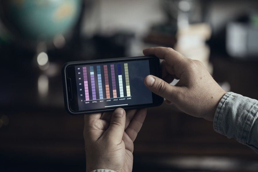 Hands holding a smartphone that shows a bar chart